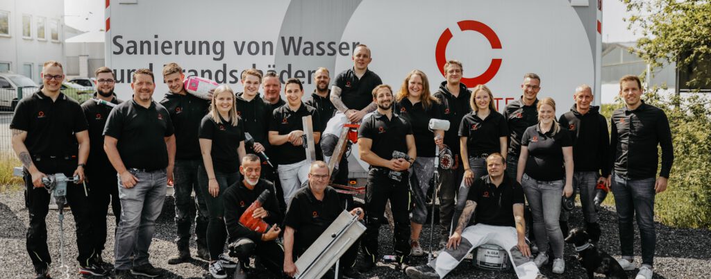 Das Team macht Karriere bei WABRA TEC und steht mit den jeweiligen Arbeitsmaterialien vor dem Logo des Unternehmenens.