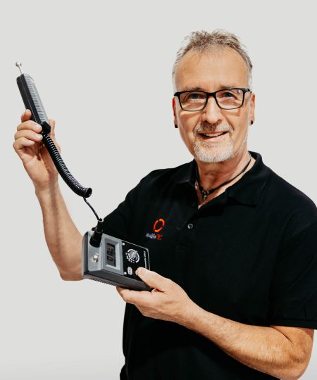 Ein Trocknungstechniker der Firma WABRA TEC hat ein schwarzes T-Shirt mit Firmenlogo an und hält in den Händen ein Gerät zur Feuchtigkeitsmessung.